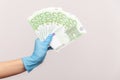 Profile side view closeup of human hand in blue surgical gloves holding and showing fan of european union Euro money in hand