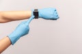 Profile side view closeup of human hand in blue surgical gloves holding and showing wirst smart watch and pointing at empty screen Royalty Free Stock Photo