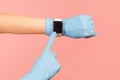 Profile side view closeup of human hand in blue surgical gloves holding and showing wirst smart watch and pointing at empty screen Royalty Free Stock Photo