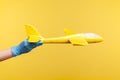 Profile side view closeup of human hand in blue surgical gloves holding yellow airplane model Royalty Free Stock Photo