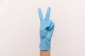 Profile side view closeup of human hand in blue surgical gloves showing victory, peace sign or number 2 with fingers Royalty Free Stock Photo