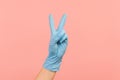 Profile side view closeup of human hand in blue surgical gloves showing victory, peace sign or number 2 with fingers Royalty Free Stock Photo