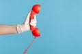 Profile side view closeup of human hand in white surgical gloves holding and showing red cale telephone handset receiver Royalty Free Stock Photo