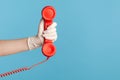 Profile side view closeup of human hand in white surgical gloves holding and showing red cale telephone handset receiver Royalty Free Stock Photo