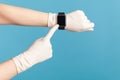 Profile side view closeup of human hand in white surgical gloves holding and showing wirst smart watch and pointing at empty Royalty Free Stock Photo