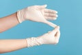 Profile side view closeup of human hand in white surgical gloves showing how to take of gloves