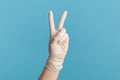 Profile side view closeup of human hand in white surgical gloves showing victory, peace sign or number 2 with fingers Royalty Free Stock Photo