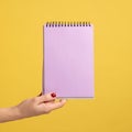 Profile side view closeup of woman hand holding purple notepad in hand and showing empty paper. Royalty Free Stock Photo
