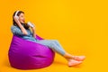 Profile side view of her she nice attractive cheerful cheery wavy-haired girl sitting on bag chair listening music