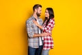 Profile side view portrait of attractive cheerful amorous couple embracing isolated over bright yellow color background
