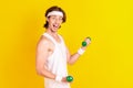 Profile side view portrait of attractive cheerful guy lifting small light dumbbell isolated over bright yellow color Royalty Free Stock Photo