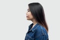 Profile side view portrait of calm serious beautiful brunette asian young woman in casual blue denim jacket with makeup standing
