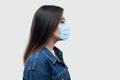 Profile side view portrait of calm serious beautiful brunette asian young woman with surgical medical mask in blue jacket standing Royalty Free Stock Photo