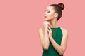 Profile side view portrait of calm serious beautiful young woman with bun hairstyle and makeup in green dress standing with closed Royalty Free Stock Photo