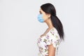 Profile side view portrait of calm young woman with medical mask in white dress standing . Protection against contagious disease, Royalty Free Stock Photo