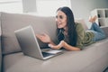 Profile side view portrait of pretty cheery girl lying on divan bare foot using laptop making video call discussing at Royalty Free Stock Photo