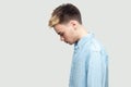 Profile side view portrait of sad upset alone handsome young man in light blue shirt standing, holding head down and depressed Royalty Free Stock Photo