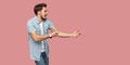 Profile side view portrait of serious screaming bearded young man in blue casual shirt standing in attack or pulling hands gesture Royalty Free Stock Photo