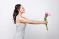 profile side view portrait of young beautiful woman in white striped dress, standing and giving tulips, looking at camera and too Royalty Free Stock Photo