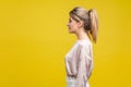 Profile side view of serious elegant young woman with ponytale hairstyle and in casual blouse,  on yellow background Royalty Free Stock Photo