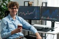 Profile of stock trader sitting against on screen, holding coffee cup. Gusher.