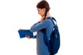 Profile of stylish happy brunette student girl with blue backpack and folder for notebooks in her hands posing isolated Royalty Free Stock Photo