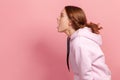 Profile of surprised brunette teen girl in hoodie looking left with big eyes and open mouth, shocked by news, empty copy space for Royalty Free Stock Photo