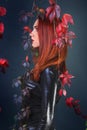 Profile of a tall red head gothic woman among the autumn vines