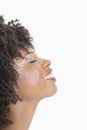 Profile view of an African American woman smiling with eyes closed against gray background