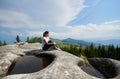 Young woman resting on a big stone in the summer day in the Carpathian mountains Royalty Free Stock Photo
