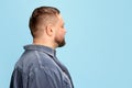 Profile view of bearded man in jeans jacket posing over light blue background. Side view Royalty Free Stock Photo