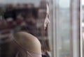 Profile view of Brunette woman behind window looking outside during epidemic quarantine Royalty Free Stock Photo