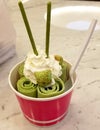 Profile view of a container of Thai rolled green ice cream topped with whipped cream and cookies. Sweet dessert. Royalty Free Stock Photo