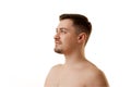 Profile view of half-naked man looking away with light smile against white studio background. Natural beauty and self Royalty Free Stock Photo