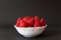Profile view of natural and sweet red strawberries in bowl, isolated on dark Royalty Free Stock Photo