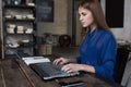 Profile view of successful young Caucasian businesswoman using a laptop, typing email, working at her modern loft Royalty Free Stock Photo