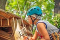 Teenage boy wearing a blue helmet and climbing gear on a ladder in a forest rope adventure park Royalty Free Stock Photo
