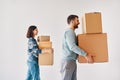 Profile view of young couple carrying cardboard boxes moving to new house on white background Royalty Free Stock Photo