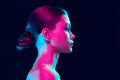 Profile view of young fashion model without makeup isolated over dark background in neon light. Concept of beauty, art Royalty Free Stock Photo