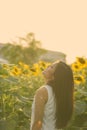 Profile view of young happy Asian woman smiling while looking up in the field of blooming sunflowers Royalty Free Stock Photo