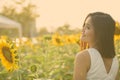 Profile view of young happy Asian woman smiling and thinking in the field of blooming sunflowers Royalty Free Stock Photo