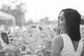 Profile view of young happy Asian woman smiling and thinking in the field of blooming sunflowers Royalty Free Stock Photo