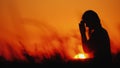 Profile of a woman in prayer at sunset Royalty Free Stock Photo