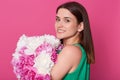 Profile of young brunette female with amazing bouquet of peonies, attractive woman wearing green sundress, has charming smile, Royalty Free Stock Photo