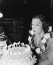 Profile of a young woman blowing off candles on a birthday cake Royalty Free Stock Photo