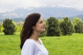 Profile of young woman with eyes closed breathing fresh air in the mountains