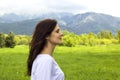 Profile of young woman with eyes closed breathing fresh air in the mountains