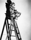 Profile of a young woman sitting on a ladder