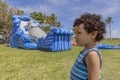 A profiled toddler stands very still with a confused look while the bounce house inflates