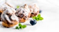 Profiterole or cream puff with filling, powdered sugar topping with berries, isolated on white background